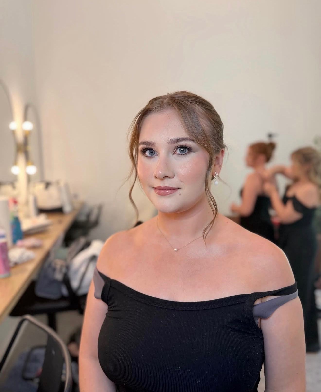 Bridesmaid in a black dress with soft glam makeup and a romantic updo