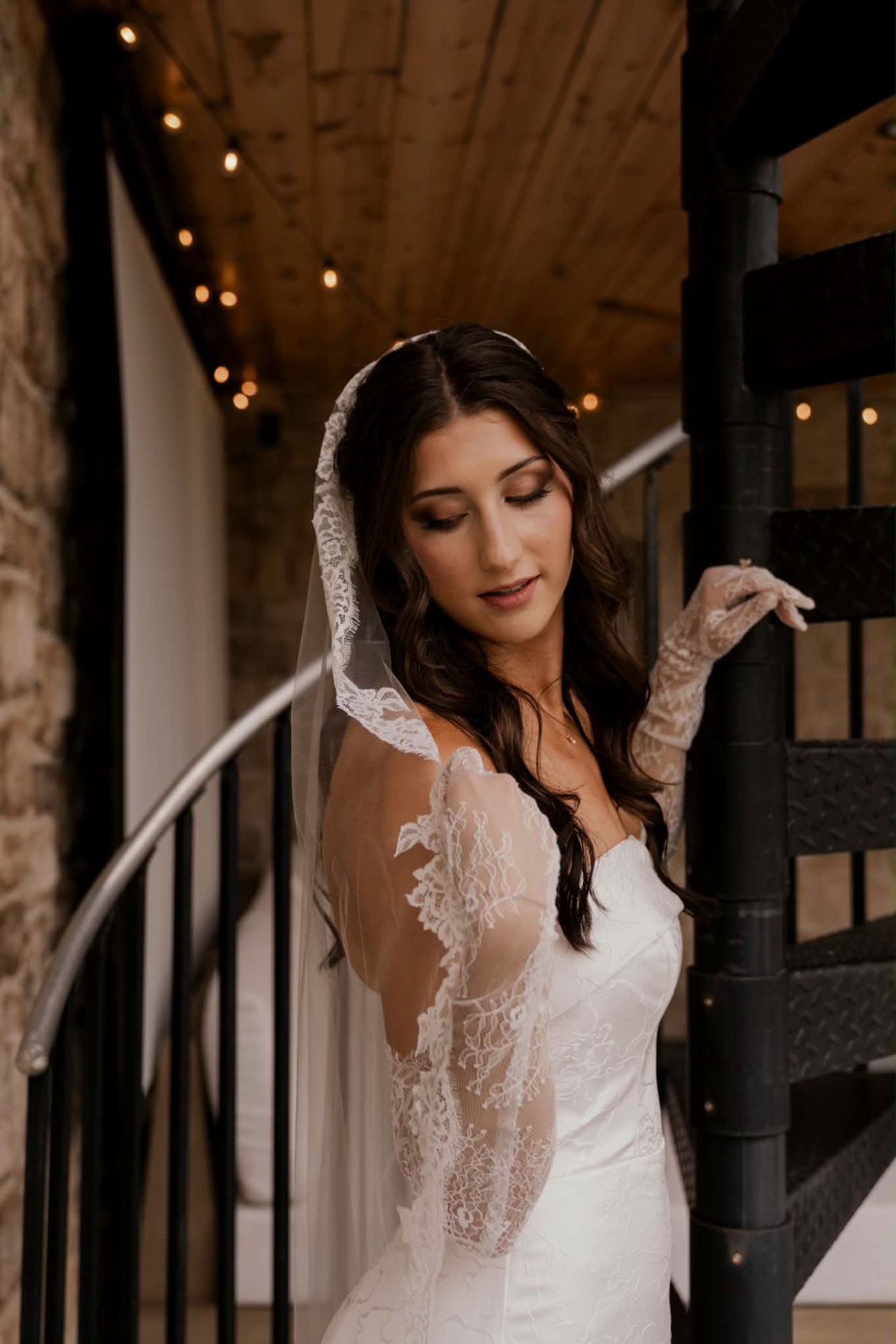Side close-up of a bride in her strapless gown and lace veil showing shimmery brown eyeshadow and blended eyeliner