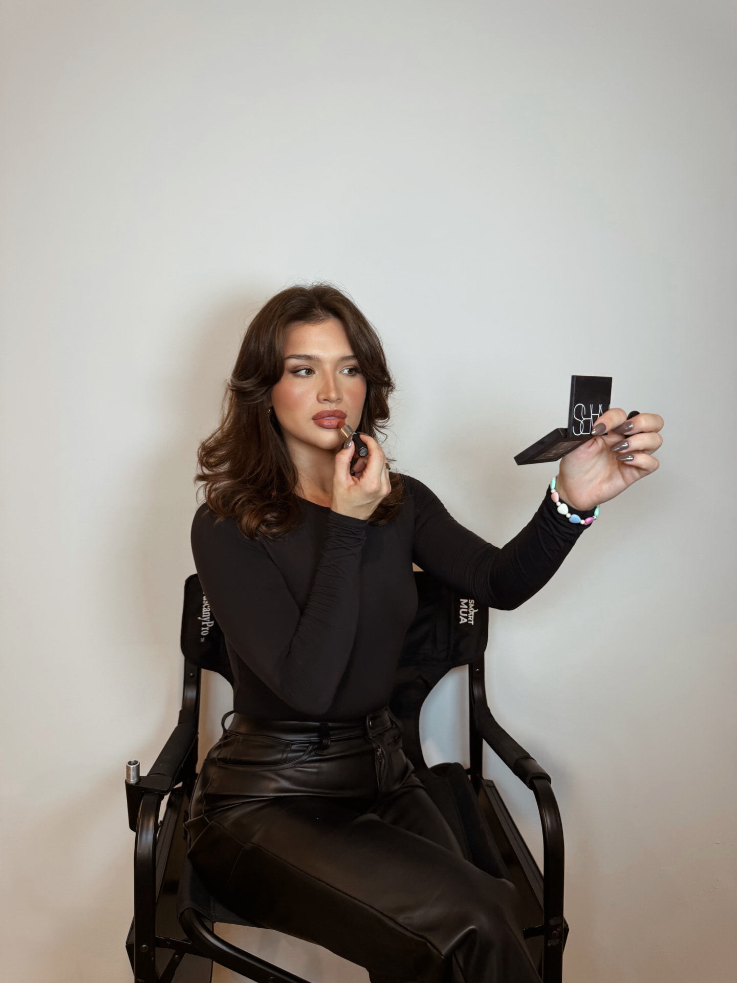 Dzenela, bridal and soft glam makeup artist and founder of Dzenelahasicmua, applying lipstick with a compact mirror
